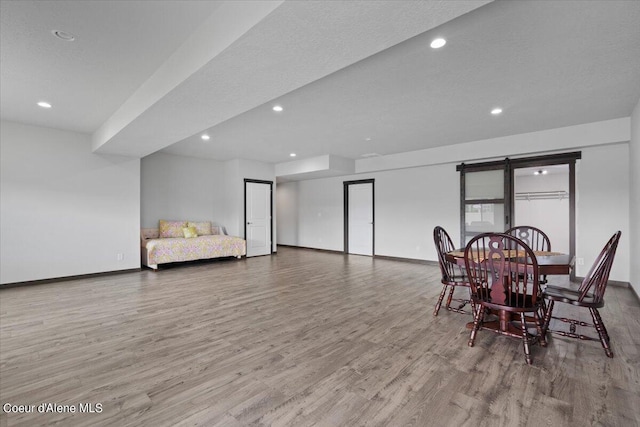 dining room with wood-type flooring, a barn door, and a textured ceiling