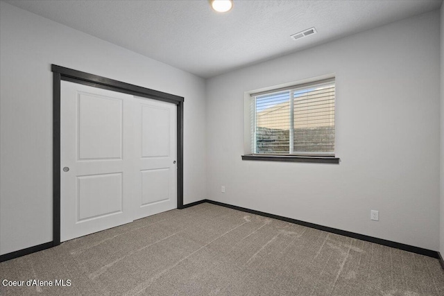 unfurnished bedroom with a closet, carpet flooring, and a textured ceiling