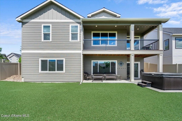 rear view of house featuring a yard, a hot tub, a patio, and a balcony