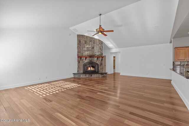 unfurnished living room featuring light hardwood / wood-style flooring, a fireplace, high vaulted ceiling, and ceiling fan