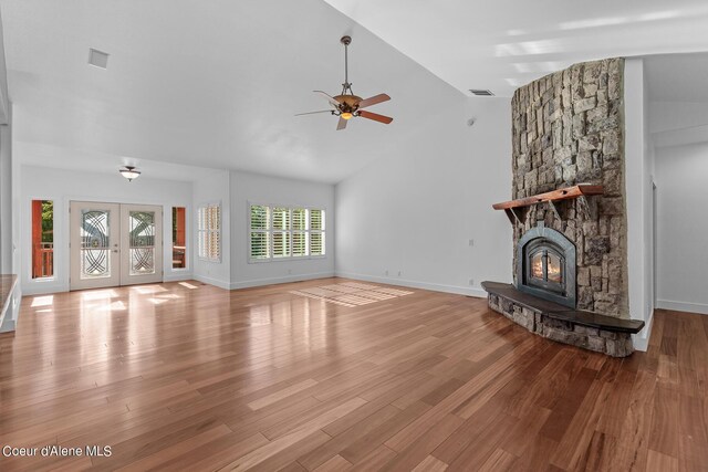 unfurnished living room featuring french doors, a fireplace, high vaulted ceiling, and light wood-type flooring