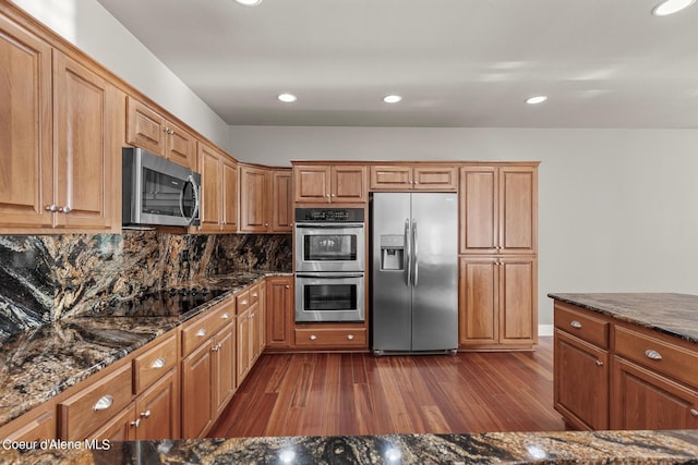 kitchen with tasteful backsplash, dark wood-type flooring, dark stone counters, and appliances with stainless steel finishes