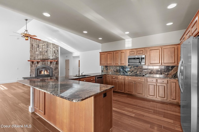 kitchen featuring stainless steel appliances, dark wood-type flooring, dark stone counters, and kitchen peninsula