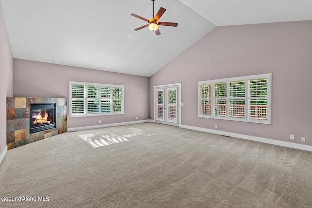 unfurnished living room featuring high vaulted ceiling, ceiling fan, a high end fireplace, light carpet, and french doors