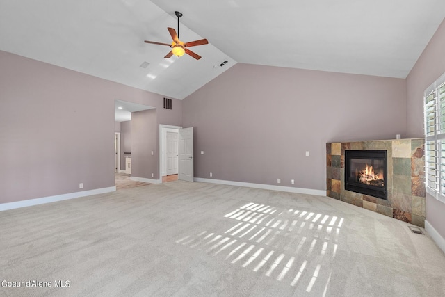 unfurnished living room featuring light carpet, high vaulted ceiling, a tile fireplace, and ceiling fan