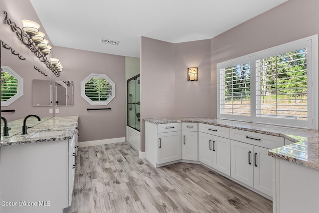 interior space with hardwood / wood-style flooring, enclosed tub / shower combo, and vanity