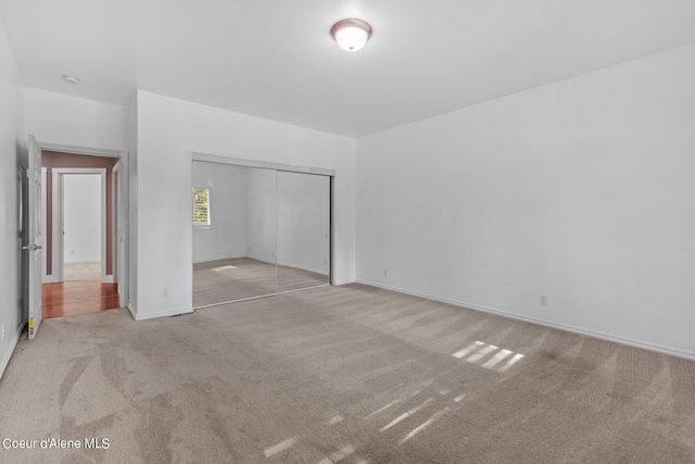 unfurnished bedroom featuring light carpet and a closet