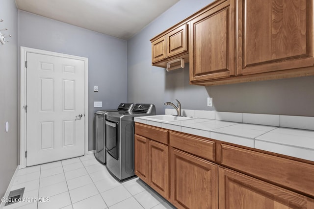 washroom with cabinets, separate washer and dryer, sink, and light tile patterned floors