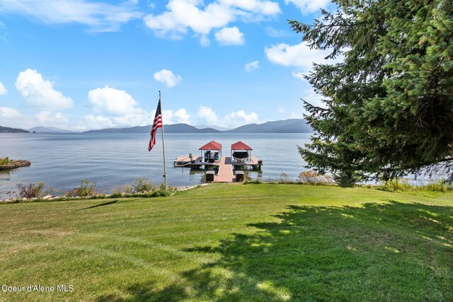 dock area with a water and mountain view and a lawn