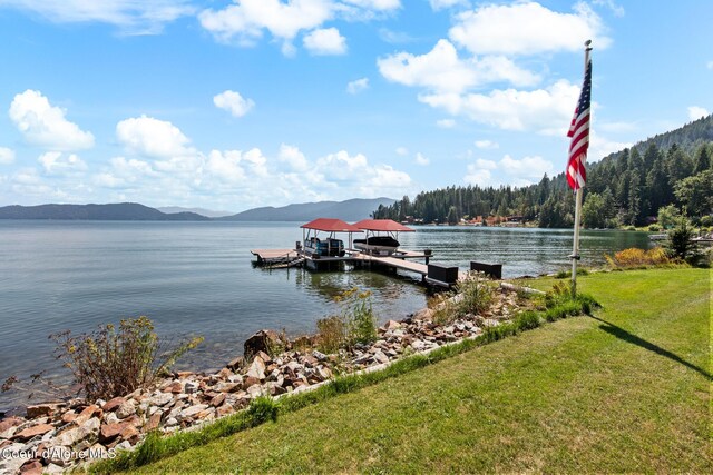 view of dock featuring a water and mountain view and a lawn