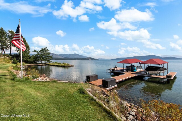 view of dock with a lawn and a water and mountain view