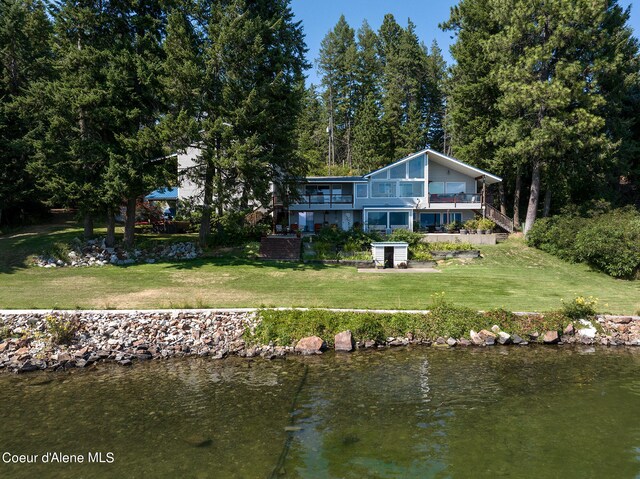 rear view of house featuring a water view and a yard