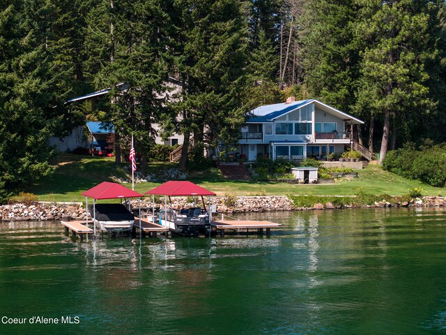 dock area featuring boat lift, a water view, and a lawn