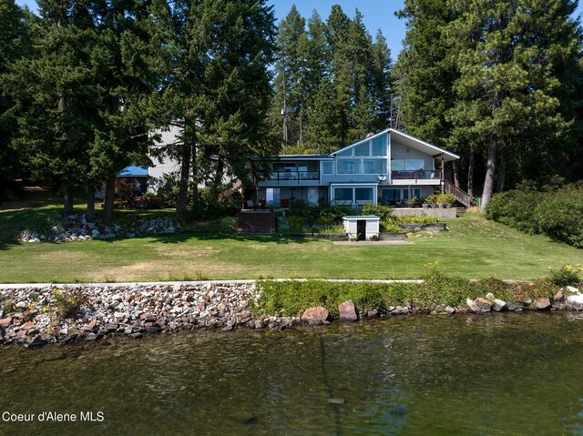 back of property with a lawn and a water view