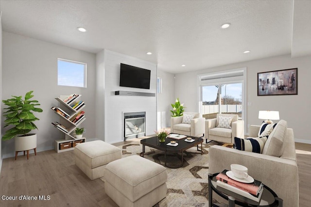 living room with hardwood / wood-style floors, a textured ceiling, and a fireplace