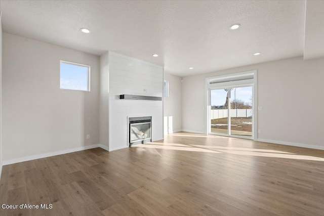 unfurnished living room with a healthy amount of sunlight, a fireplace, and wood-type flooring