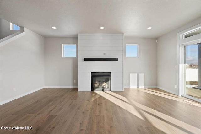 unfurnished living room featuring a large fireplace, hardwood / wood-style floors, and a textured ceiling