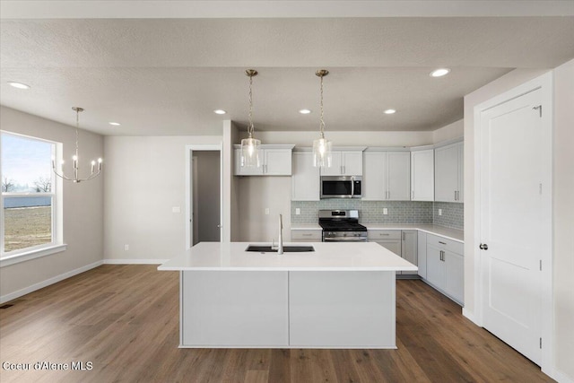 kitchen featuring sink, appliances with stainless steel finishes, a kitchen island with sink, white cabinetry, and tasteful backsplash