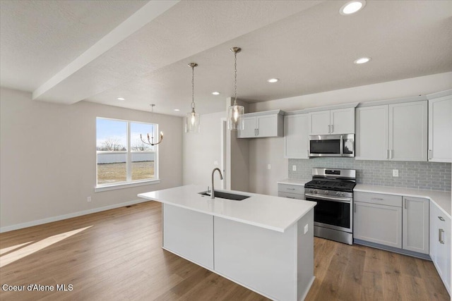 kitchen featuring tasteful backsplash, sink, hanging light fixtures, a kitchen island with sink, and stainless steel appliances