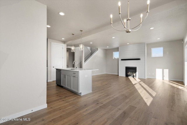 unfurnished living room featuring sink, dark wood-type flooring, a fireplace, and a notable chandelier