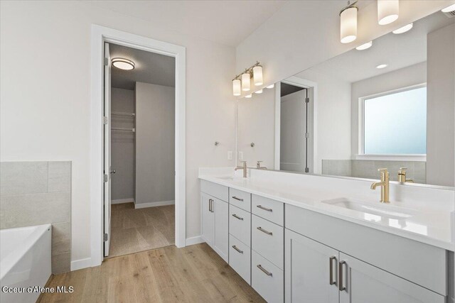 bathroom featuring hardwood / wood-style flooring, a tub to relax in, and vanity