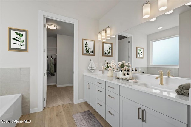 bathroom featuring hardwood / wood-style flooring, vanity, and a tub to relax in