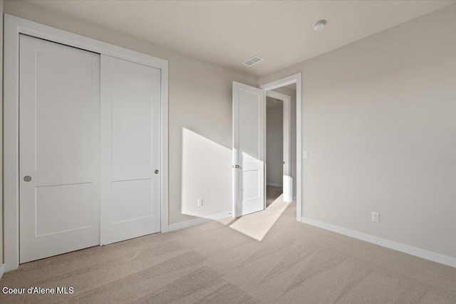 unfurnished bedroom featuring a closet and light carpet