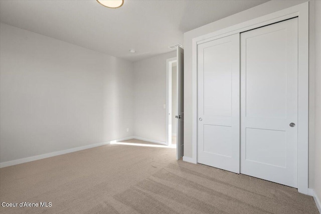 unfurnished bedroom featuring a closet and light carpet