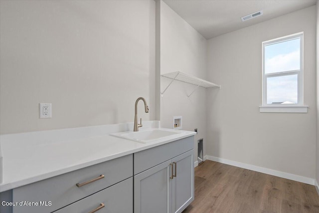 laundry room featuring sink, cabinets, hookup for a washing machine, electric dryer hookup, and light wood-type flooring