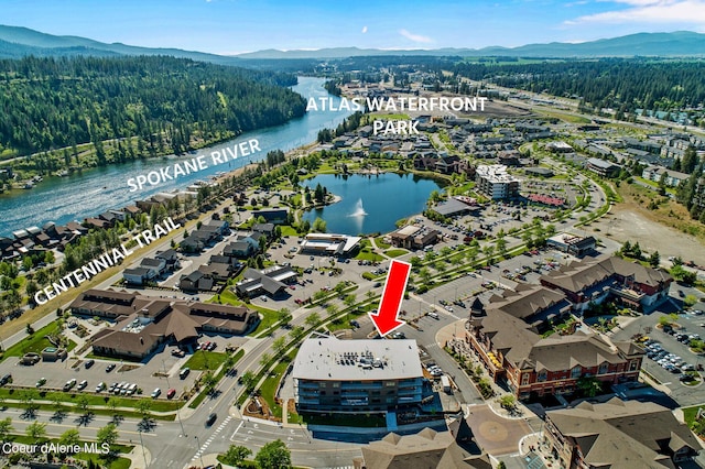 drone / aerial view featuring a forest view and a water and mountain view