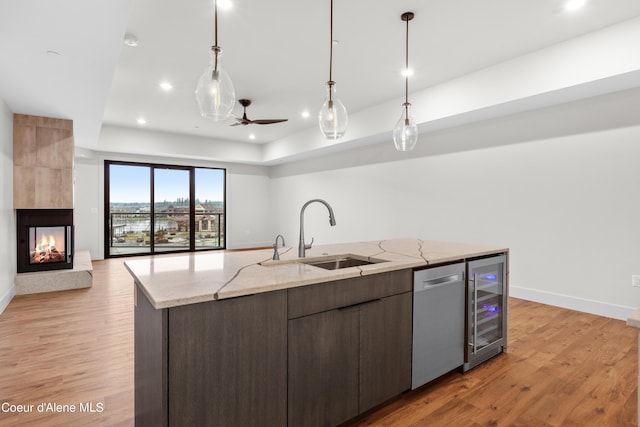 kitchen with stainless steel dishwasher, wine cooler, light wood-style floors, and a sink