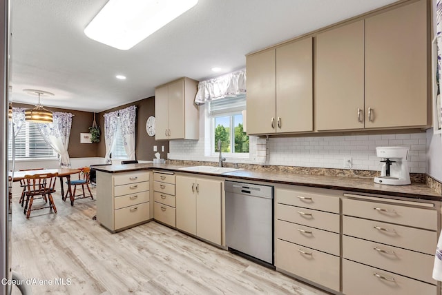 kitchen featuring dark countertops, a sink, cream cabinets, and stainless steel dishwasher