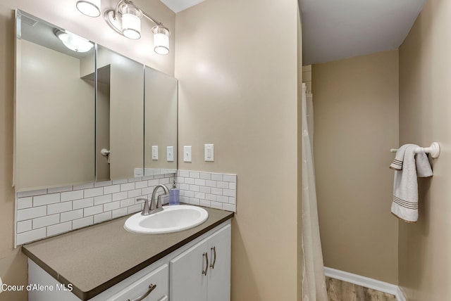 full bathroom featuring baseboards, vanity, and decorative backsplash