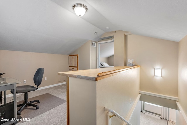 office area featuring vaulted ceiling, baseboards, visible vents, and light colored carpet