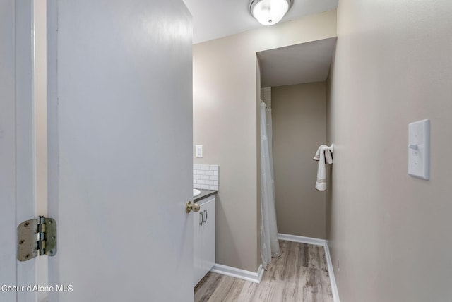 full bathroom featuring baseboards, wood finished floors, and vanity