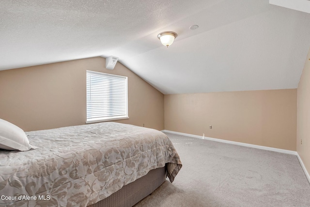 bedroom featuring lofted ceiling, carpet floors, a textured ceiling, and baseboards