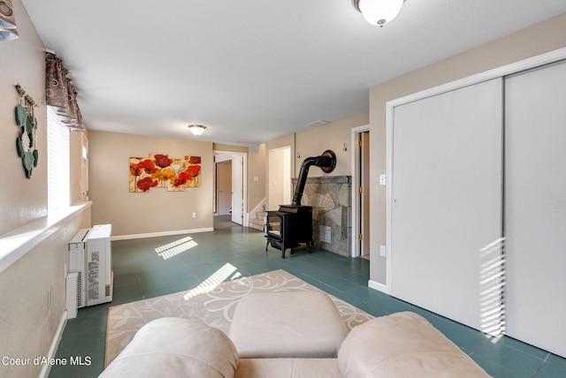 living room featuring a wood stove, baseboards, and dark tile patterned flooring