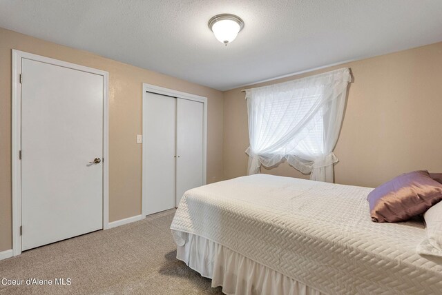 bedroom with a textured ceiling, a closet, carpet, and baseboards