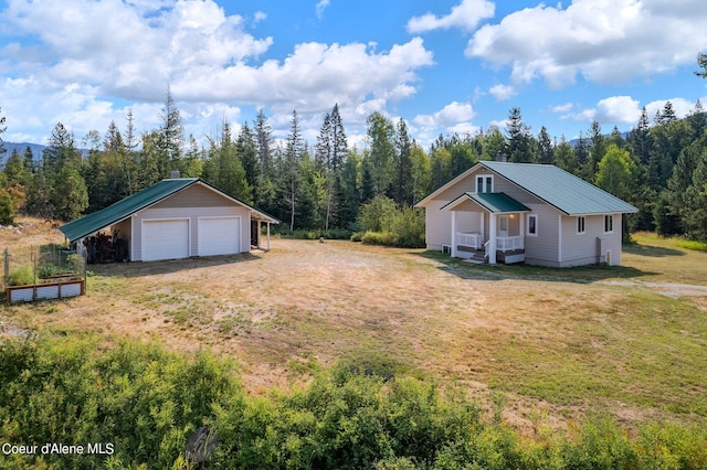 view of yard with a garage, a forest view, an outdoor structure, and a garden