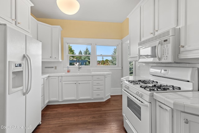 kitchen featuring white cabinetry, white appliances, sink, dark hardwood / wood-style floors, and tile countertops