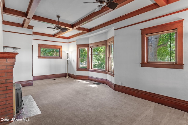 unfurnished living room with light colored carpet, ceiling fan, coffered ceiling, and a wood stove