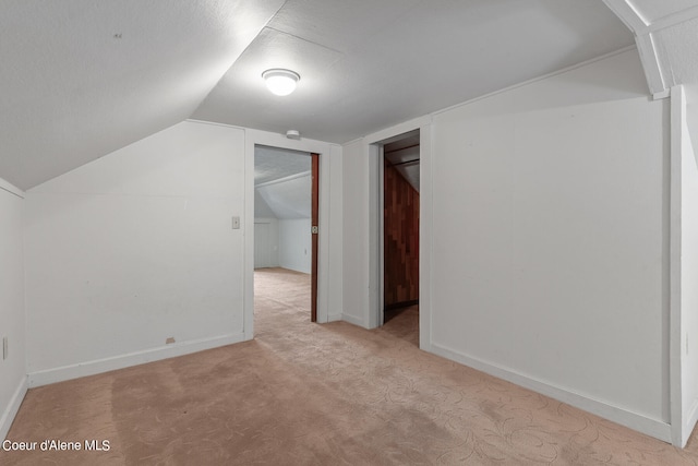 bonus room with vaulted ceiling and light colored carpet