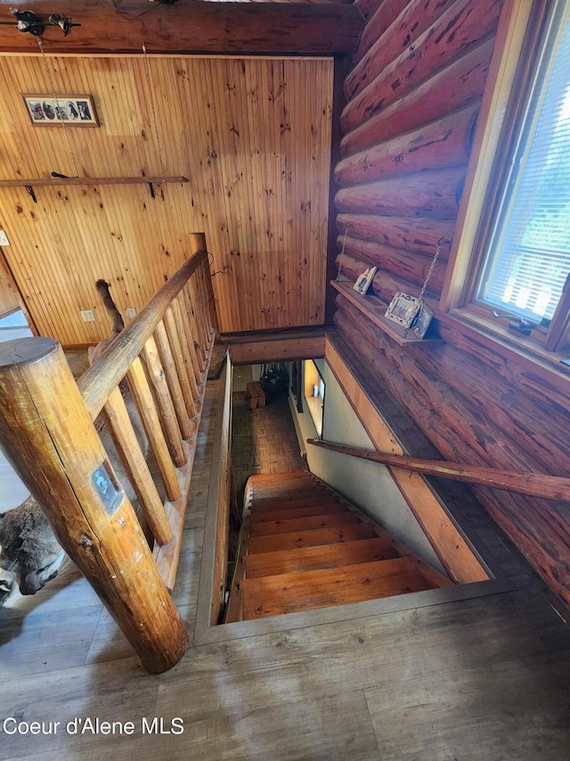 stairs featuring hardwood / wood-style flooring and rustic walls