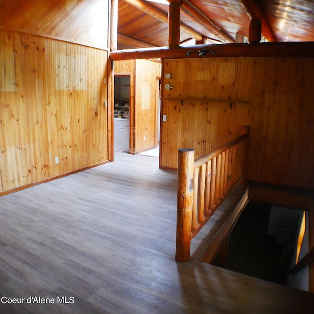 hallway featuring lofted ceiling with beams, wood-type flooring, wooden ceiling, and wooden walls