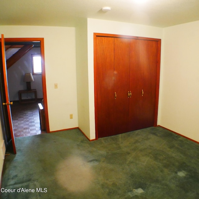 unfurnished bedroom with dark carpet and a closet