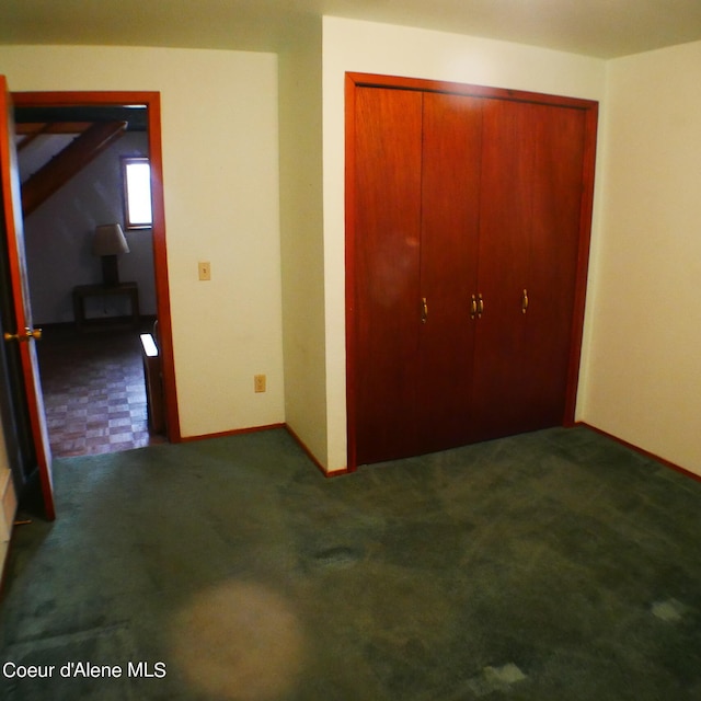 unfurnished bedroom featuring a closet and dark carpet