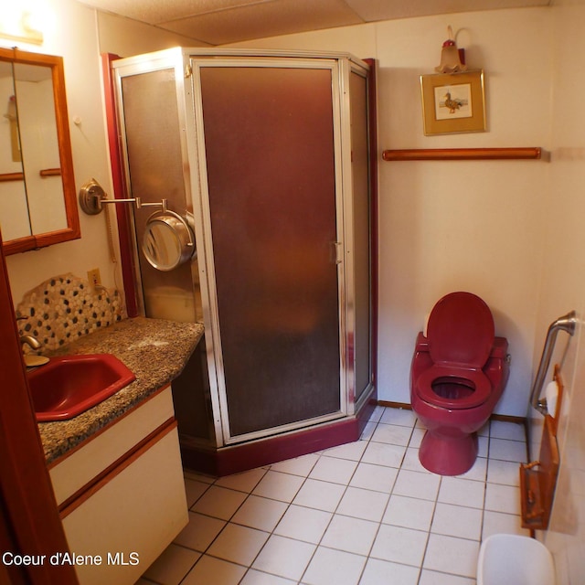 bathroom featuring tile patterned flooring, vanity, toilet, and walk in shower