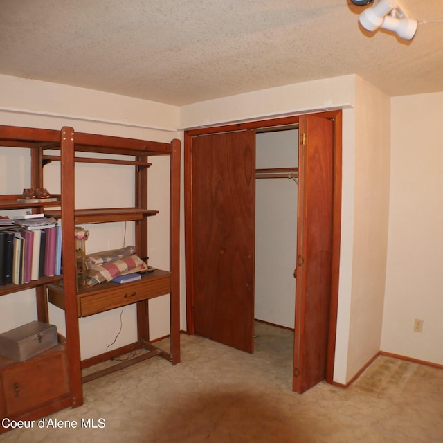 unfurnished bedroom featuring a textured ceiling, light carpet, and a closet