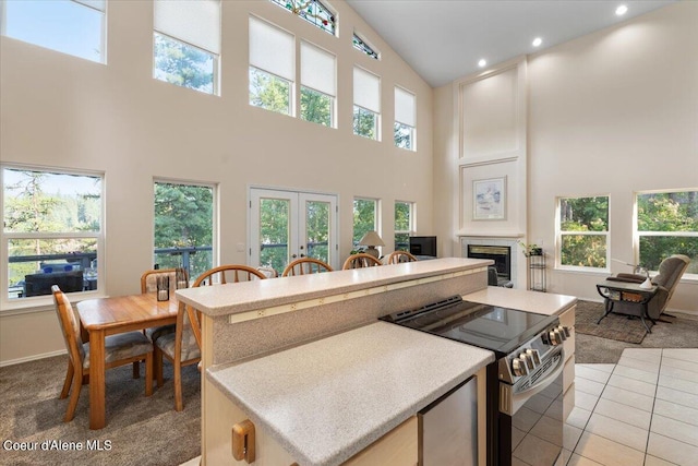 kitchen with a kitchen island, a healthy amount of sunlight, stainless steel electric range oven, and light tile patterned floors