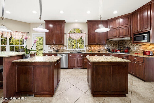 kitchen with backsplash, stainless steel appliances, pendant lighting, and a kitchen island